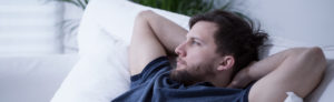 Panoramic view of thoughtful man lying on bed